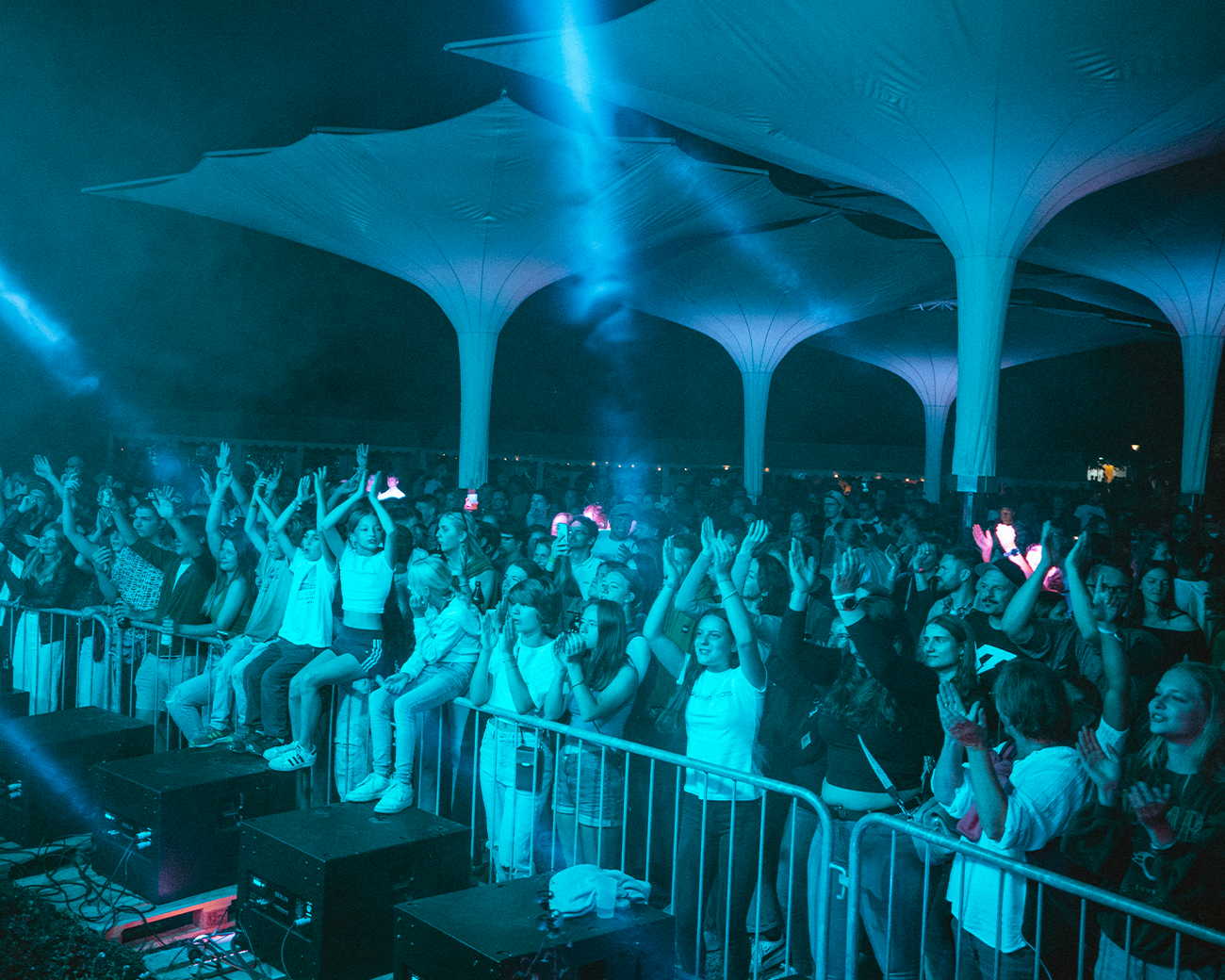 Menschenmenge unter Schirmen blau angeleuchtet von Bühnenlicht